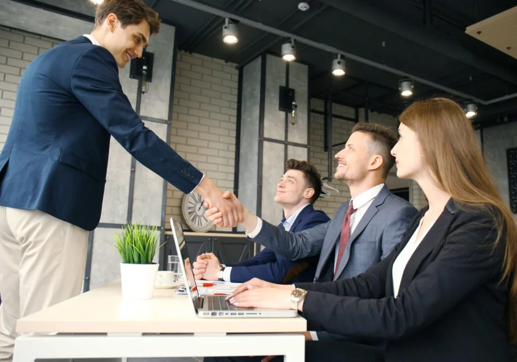 Professionals shaking hands to close a service agreement in a modern office