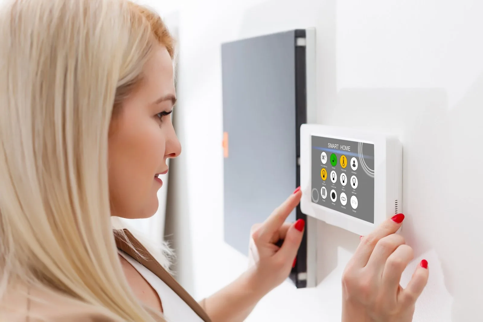 Woman using a smart home intercom panel to control her house