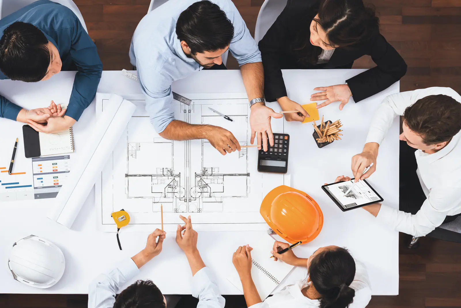 Design team gathered around architectural drawings, seen from above