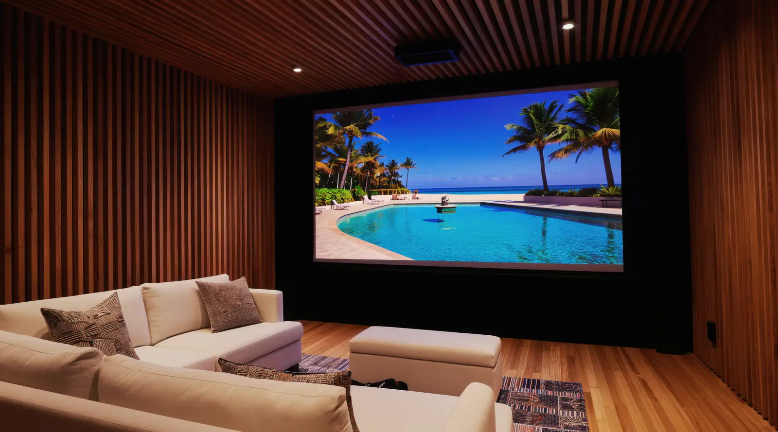 A media room lined in warm wood slats, with a deep sofa facing a large screen