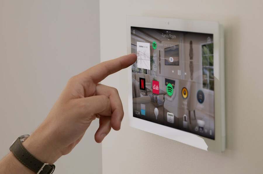 A man is adjusting the settings of his Control4 system from a touch panel installed in the wall.
